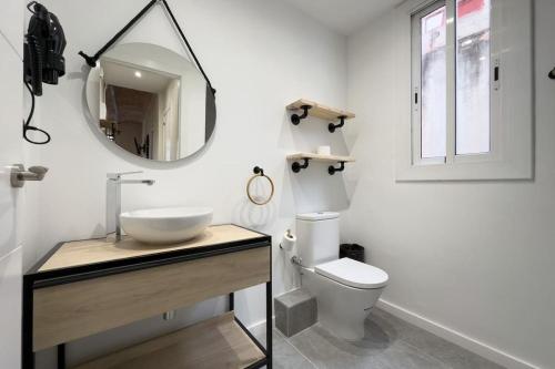 y baño con lavabo, espejo y aseo. en New 2 bedroom apartment in Plaza España, en Barcelona