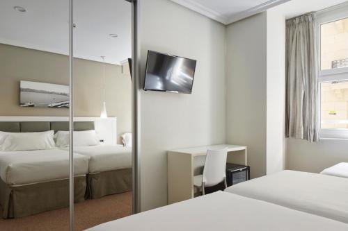 a hotel room with two beds and a mirror at Pensión Alemana in Donostia-San Sebastián