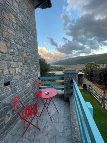 een patio met een rode tafel en stoelen aan een stenen muur bij Helga's Guesthouse in Lin