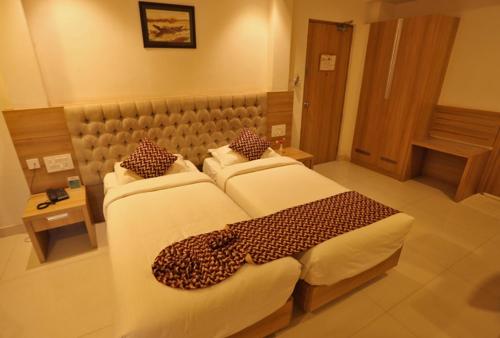 a hotel room with two beds with leopard pillows at Hotel Anjali Park in Kottayam