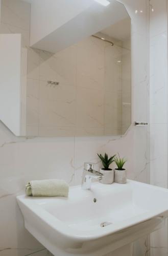 a white bathroom with a sink and a mirror at Kaliva Residence in Kalamaki