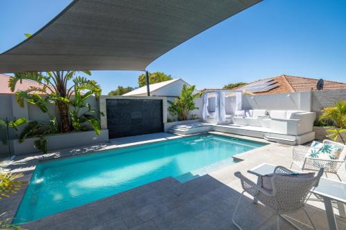 a swimming pool with a patio furniture and an umbrella at Mindarie Retreat in Mindarie