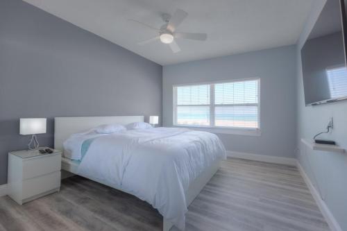 a white bedroom with a bed and a window at Sea La Vie Beach Oceanfront Patio Pet Friendly in Jacksonville Beach