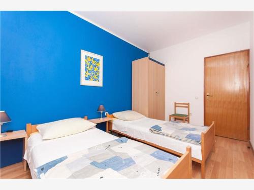 two beds in a room with a blue wall at Apartment Zora in Vodice