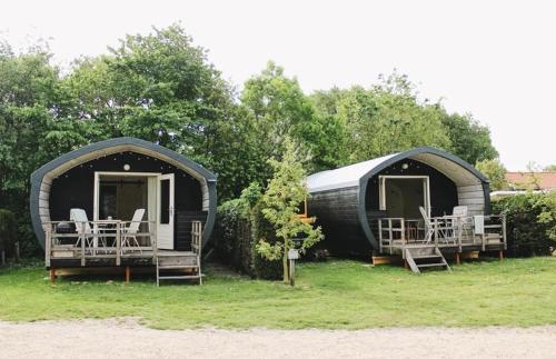 a couple of black homes sitting in the grass at CoCon in Scharendijke