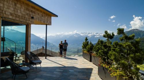 two people standing on a balcony looking at the mountains at Panoramahotel Watles in Malles Venosta