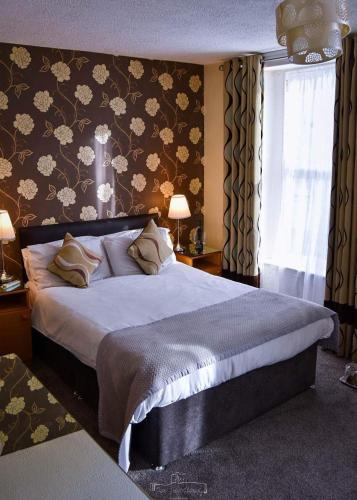 a bedroom with a large bed with floral wallpaper at Dobbins Inn in Carrickfergus