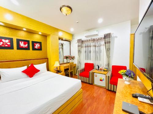 1 dormitorio con cama, escritorio y sillas rojas en Moon Hotel Cau Giay en Hanói