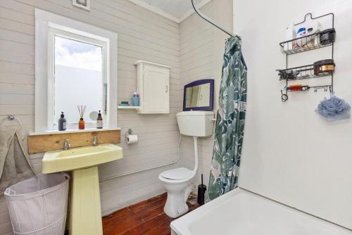 a bathroom with a sink and a toilet at Cox Bay Cottage in Raglan