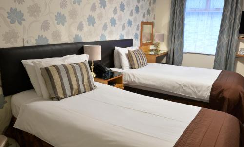 ein Hotelzimmer mit zwei Betten und einem Fenster in der Unterkunft Dobbins Inn in Carrickfergus