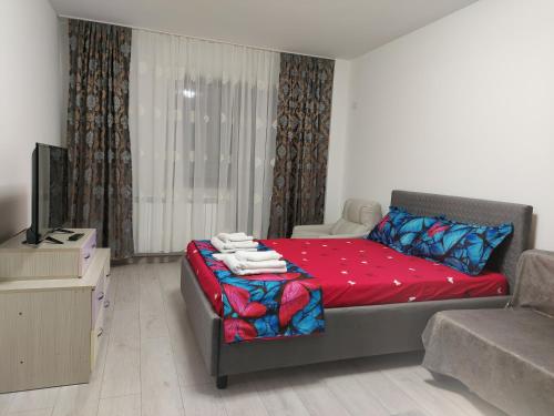 een slaapkamer met een bed met rode lakens en een televisie bij Bya Brown Residence in Valea Lupului