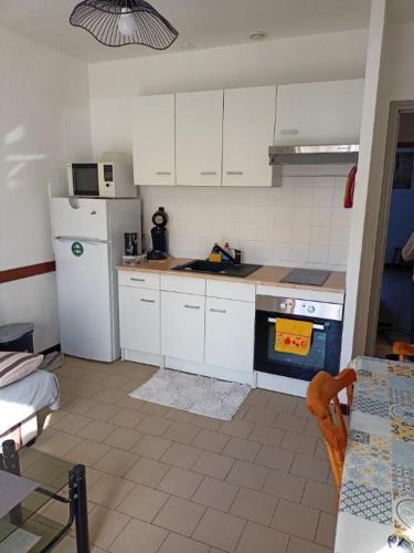 a kitchen with white cabinets and a blue stove top oven at Appartement 4 personnes Vieux-Boucau in Vieux-Boucau-les-Bains