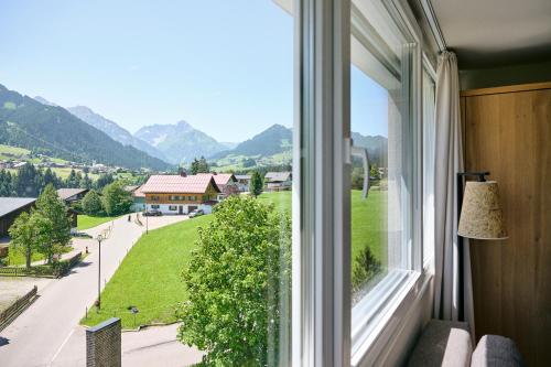 a window with a view of a street and mountains at Genuss- & Aktivhotel Sonnenburg in Riezlern