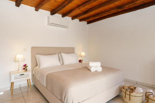 a white bedroom with a bed and a night stand at Villa Maria - Hydra Dream Houses in Hydra