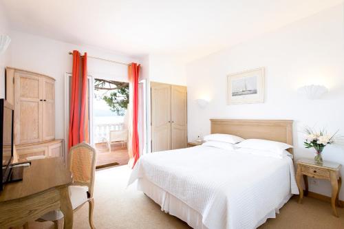 a bedroom with a bed and a desk and a television at Hôtel Les Mouettes - Teritoria in Ajaccio