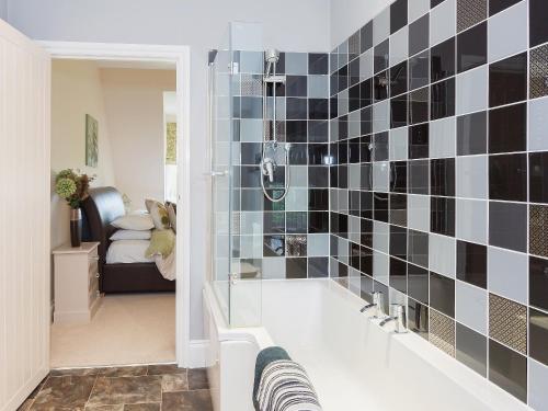 a bathroom with a black and white tiled wall at Yokefleet Cottage in Eastrington