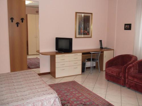 a room with a desk with a television and a couch at Hotel Residence La Fontana in Mariano Comense