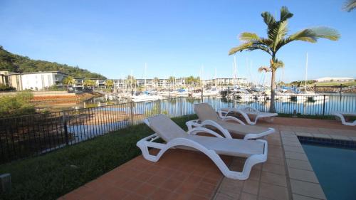 - un ensemble de chaises longues installées à côté de la piscine dans l'établissement Unit 12 Beachside Apartments, à Nelly Bay