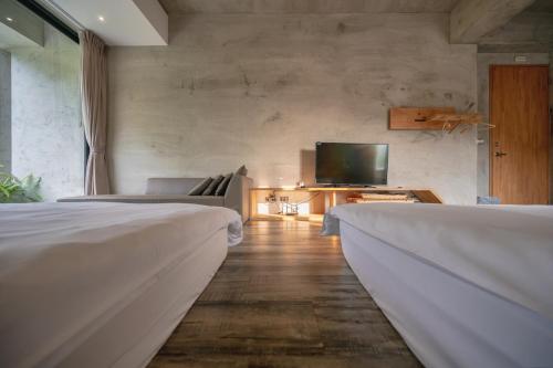 two beds in a room with a tv and a couch at 日月潭山慕藝旅 Sun Moon Inn in Yuchi