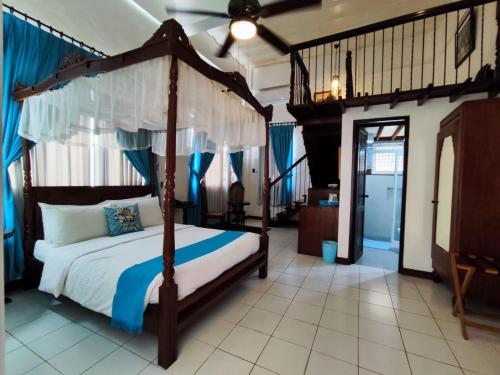 a bedroom with a canopy bed with blue curtains at Paradores Del Castillo in Taal