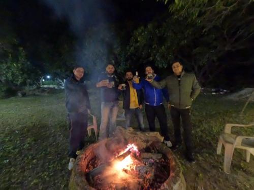 a group of men standing around a fire at night at CAMP BIG CAT CORBETT, Hotel Resort booking, Dhikuli, Near Kosi River, garjiya Bijrani Sitabani Safari ZonesJim Corbett Park, Ramnagar in Garjia