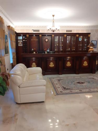 a living room with a white chair and wooden cabinets at Hotel Guri in Elbasan