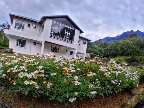 a house with a bunch of flowers in front of it at Sling N Stone Vacation Homes, Mt Kinabalu in Kundasang