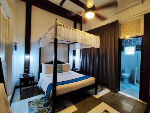 Schlafzimmer mit Himmelbett und Bad in der Unterkunft Paradores Del Castillo in Taal