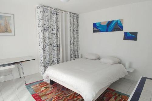 Habitación blanca con cama y escritorio en Comme à la maison en Cenon