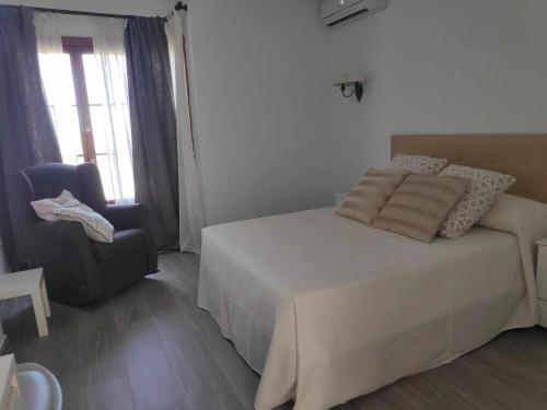 a bedroom with a white bed and a chair at Sonsoles Apartamentos Bahía Sur in San Fernando