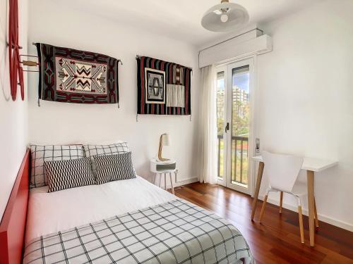 a bedroom with a bed and a desk and a window at Private Sunset Terrace & Ocean Cliff Pool Garden at Designer Apt by LovelyStay in Funchal