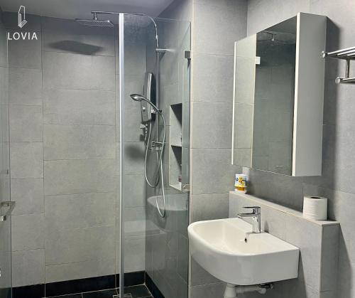 ein Bad mit einer Dusche, einem Waschbecken und einem Spiegel in der Unterkunft Jesselton Quay KK SEA VIEW or CITY VIEW by LOVIA in Kota Kinabalu