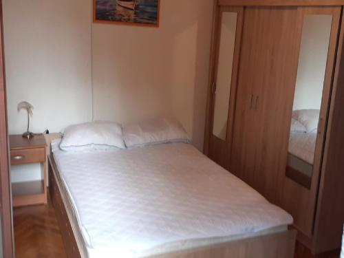 a small bedroom with a bed and a mirror at Apartments Rudi in Klenovica