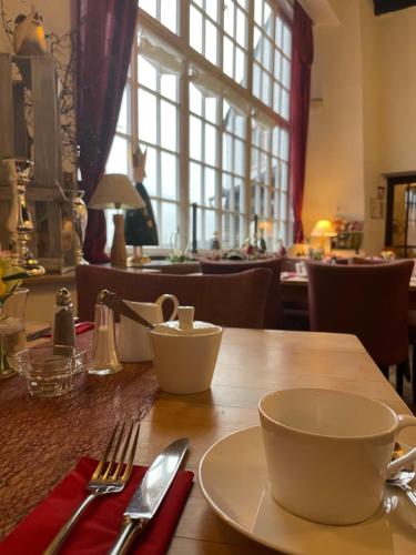 a wooden table with a plate and a cup on it at Burghaus & Villa Kronenburg in Kronenburg