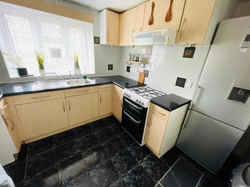 a small kitchen with a stove and a refrigerator at Cosy Flat Close To East Finchley Station in London