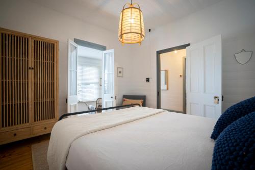 - une chambre avec un grand lit blanc et un lustre dans l'établissement Cosy coastal cottage- Allwood Harbour, à Kiama