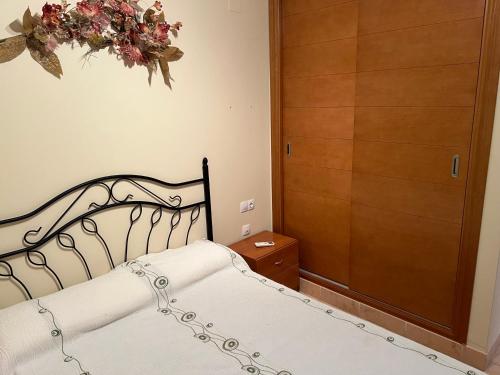 - une chambre dotée d'un lit avec une couronne de fleurs sur le mur dans l'établissement Residencial Los Almendros Playa Romana, à Alcossebre
