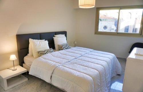 une chambre avec un grand lit blanc et une fenêtre dans l'établissement LEM5D - Palmes d'Or Properties, à Cannes