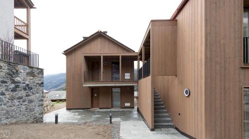 una casa con pareti in legno e una scala tra due edifici di Italianway - Dosso del Grillo 1A a Valdidentro