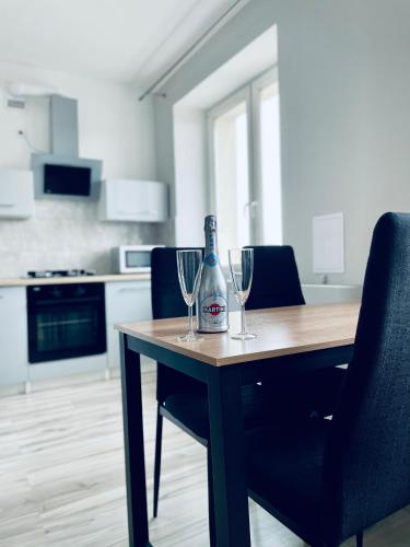 a bottle of wine sitting on a table with two wine glasses at Apartament z sypialnią Giżycko in Giżycko