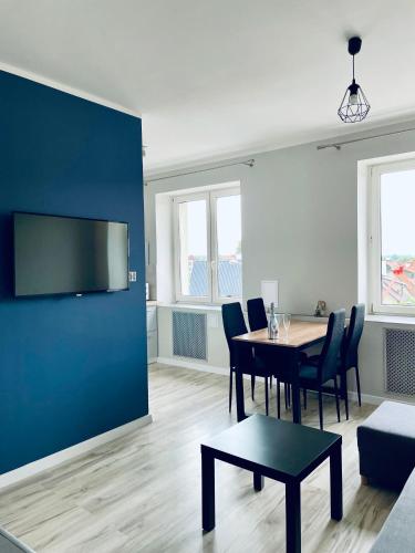 a living room with a table and a blue wall at Apartament z sypialnią Giżycko in Giżycko