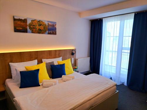 a bedroom with a large bed with yellow and blue pillows at Hotel Svět in Třeboň