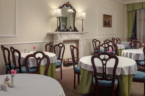 a dining room with tables and chairs and a fireplace at Spa Hotel Villa Smetana in Karlovy Vary