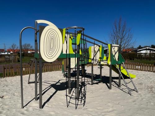 a playground in the sand with a play system at Camping-Caravaning de la Mollière in Groffliers