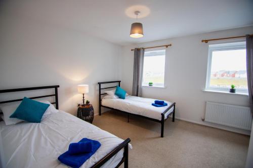 a bedroom with two beds and two windows at Old Sarum House in Old Sarum