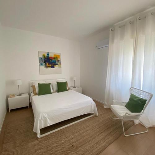 una camera bianca con un letto bianco e una sedia di WHITE LOTUS Apartment a Taormina