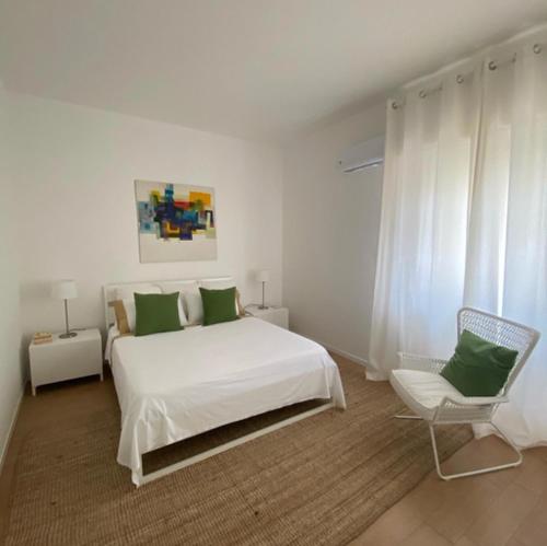 a white bedroom with a white bed and a chair at WHITE LOTUS Apartment in Taormina