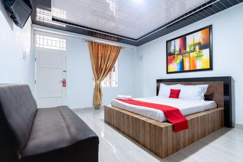 1 dormitorio con cama y sofá en RedDoorz near Universitas Simalungun Pematangsiantar, en Pematangsiantar