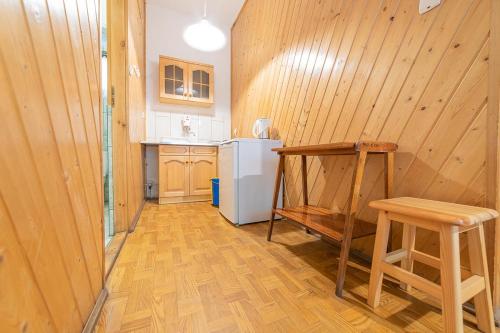 a kitchen with wooden walls and a wooden table and stool at Ośrodek Wrzosowa Góra - domki in Ruciane-Nida