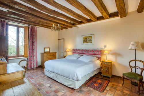 a bedroom with a large white bed and a chair at La Fauconnerie Du Roy in Montainville